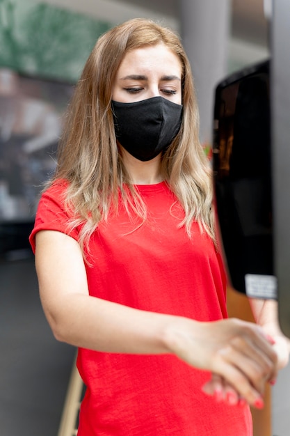 Donna al centro commerciale con maschera utilizzando disinfettante per le mani