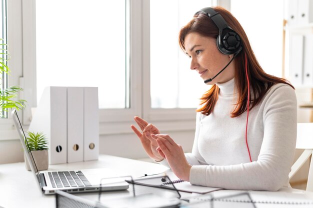 Donna al lavoro che ha videochiamata sul computer portatile