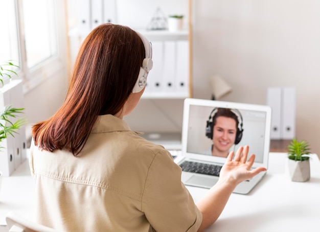 Donna al lavoro che ha videochiamata sul computer portatile