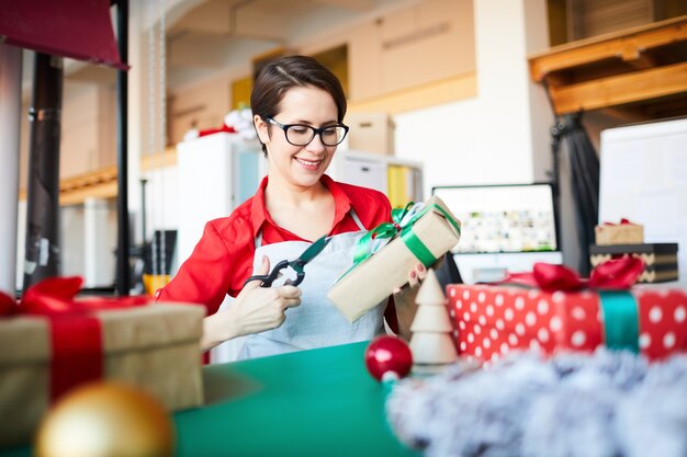 donna al lavoro, fare una ghirlanda di Natale e confezionare regali