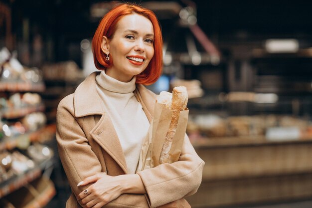 Donna al supermercato che compra pane fresco