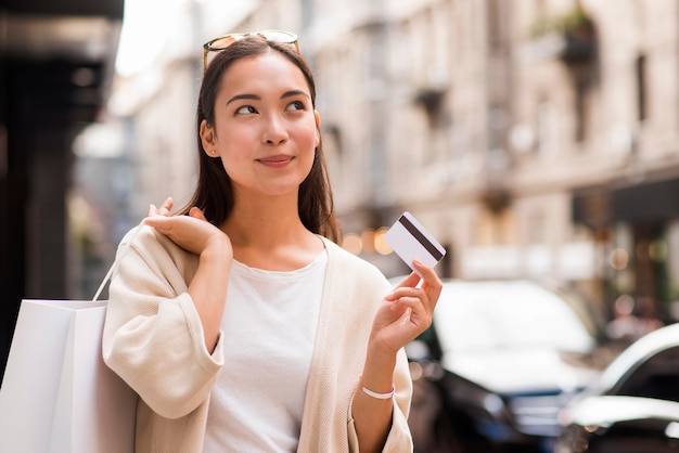 Donna all'aperto che tiene la carta di credito e la borsa della spesa