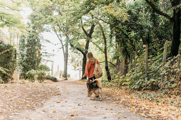 Donna alla moda a fare una passeggiata con il suo cane