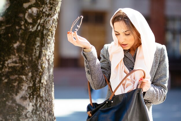 Donna alla moda alla ricerca di qualcosa nella sua borsa