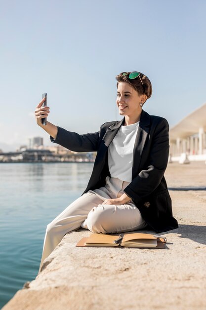 Donna alla moda che controlla il suo telefono all'aperto