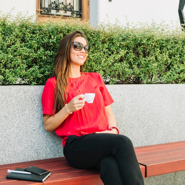 Donna alla moda che si siede sul banco bevendo caffè