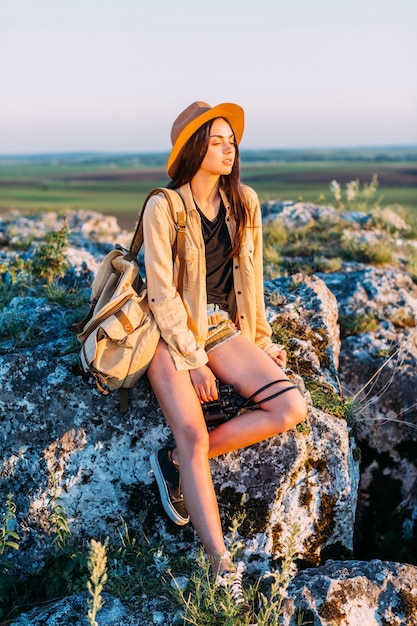 Donna alla moda che si siede sulla roccia