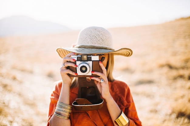 Donna alla moda con fotocamera retrò nel deserto