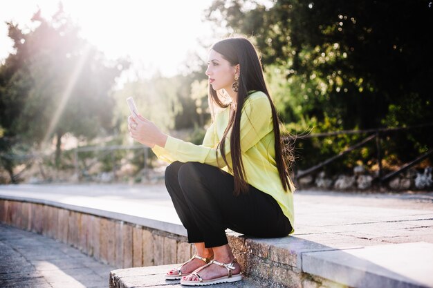 Donna alla moda con il telefono nel parco