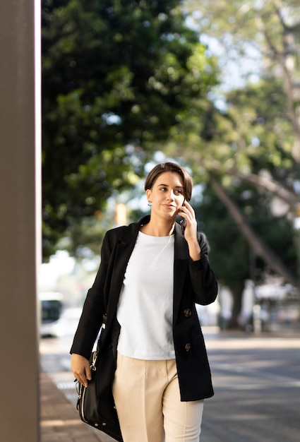 Donna alla moda di smiley che parla sul telefono all'aperto