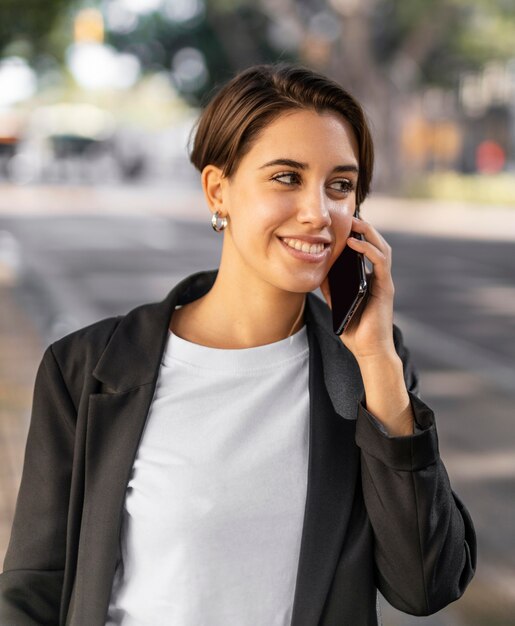 Donna alla moda di smiley che parla sul telefono all'aperto