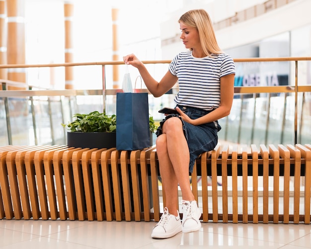 Donna alla moda di vista frontale che controlla i sacchetti della spesa