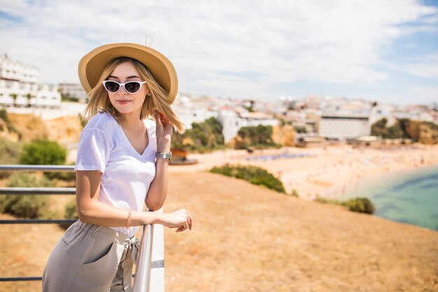 Donna alla moda in spiaggia estiva in una giornata calda in cappello estivo e occhiali da sole