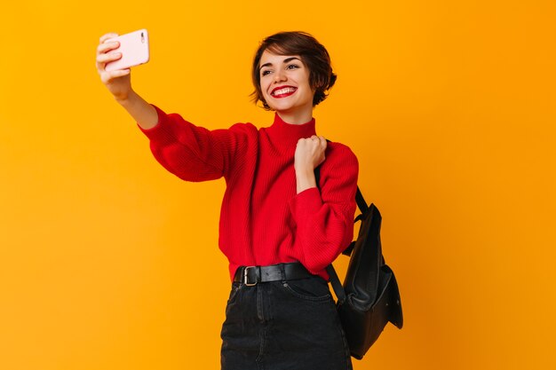 Donna alla moda ispirata con i capelli corti che prendono selfie