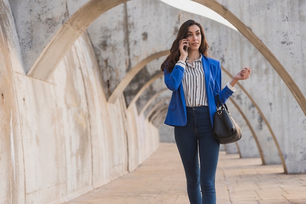 Donna alla moda parla al telefono, fuori