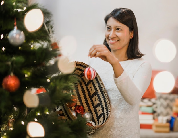 Donna allegra che decora l'albero di Natale