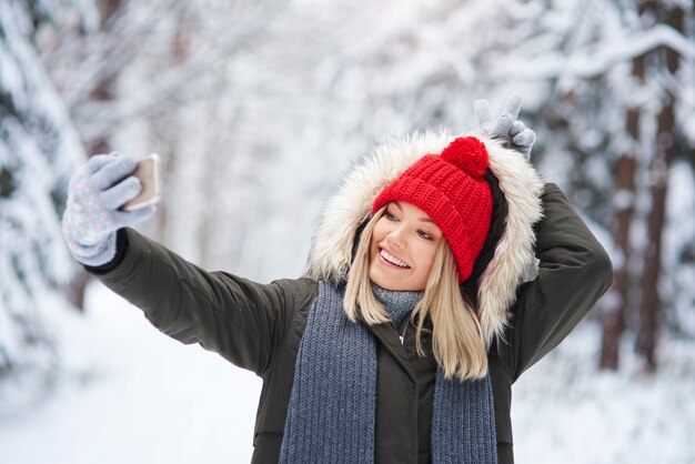 Donna allegra che fa un selfie nella foresta di inverno