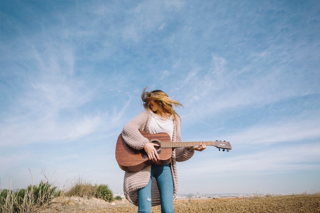 Donna allegra che gioca chitarra in campagna