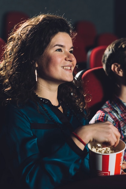Donna allegra che mangia popcorn nel cinema