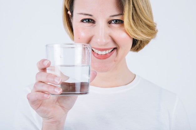 Donna allegra che mostra bicchiere d&#39;acqua