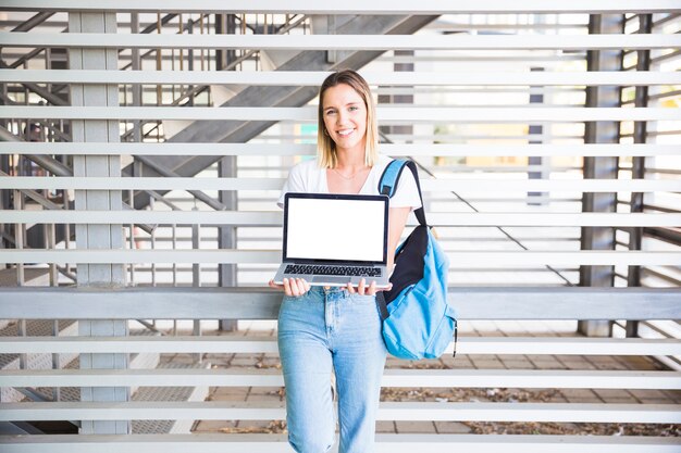 Donna allegra che mostra computer portatile alla macchina fotografica