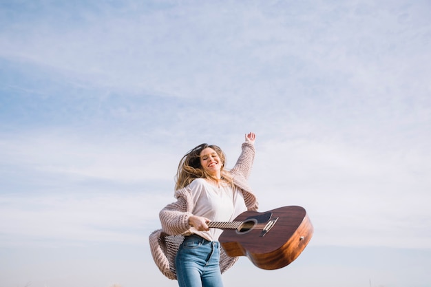 Donna allegra che salta con la chitarra