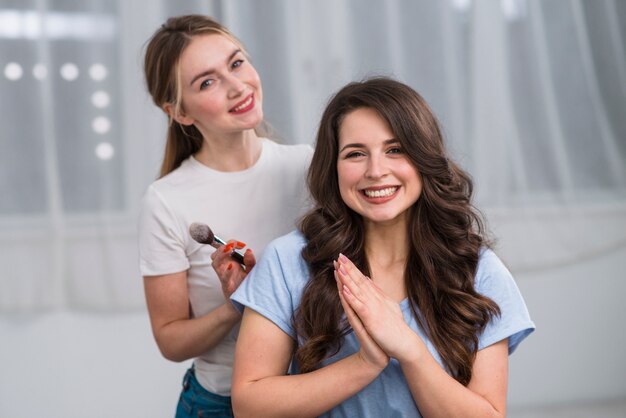 Donna allegra e visagiste che sorride alla macchina fotografica