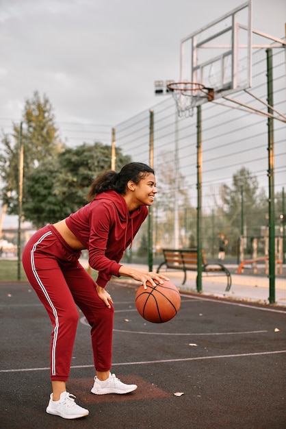 Donna americana nera che gioca a basket su un campo