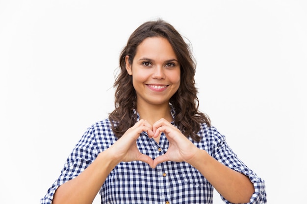 Donna amichevole felice che fa forma del cuore con le mani