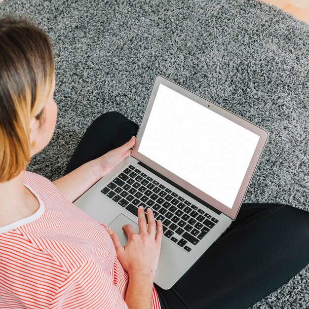 Donna anonima che per mezzo del computer portatile sul pavimento