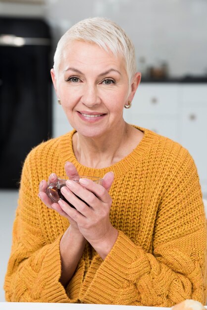 Donna anteriore che posa e che sorride mentre tenendo la tazza di caffè