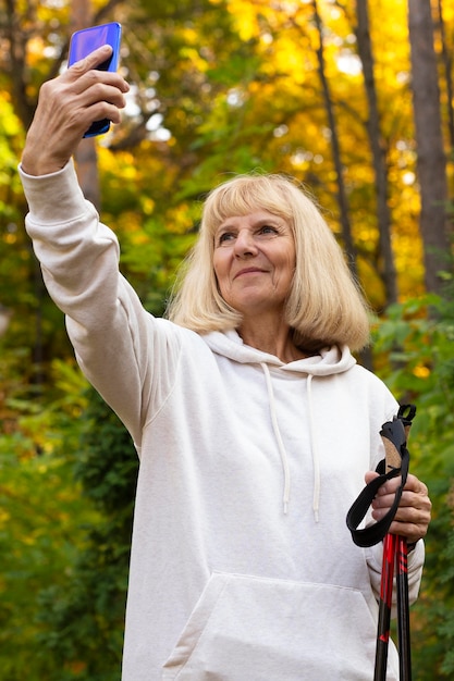 Donna anziana all'aperto prendendo selfie durante il trekking