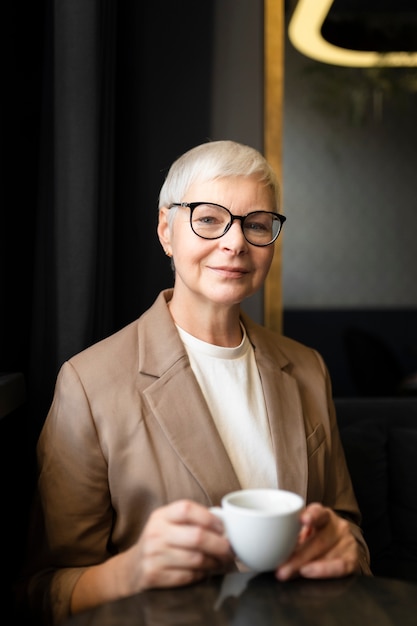 Donna anziana che beve caffè durante un raduno