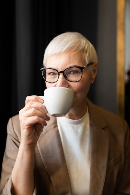 Donna anziana che beve caffè durante un raduno