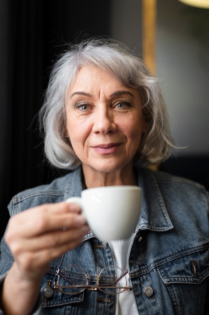 Donna anziana che beve caffè durante un raduno