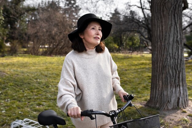 Donna anziana che cammina con la sua bici