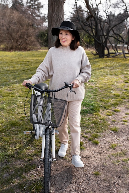 Donna anziana che cammina con la sua bici