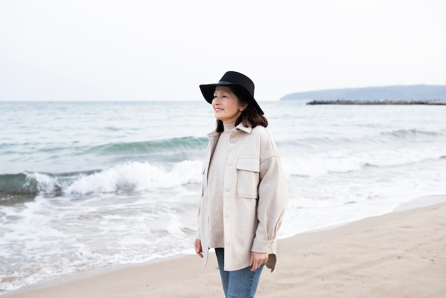 Donna anziana che cammina in riva al mare