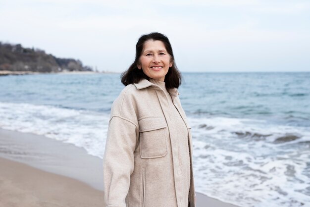 Donna anziana che cammina in riva al mare