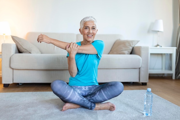 Donna anziana che fa allenamento di riscaldamento a casa Donna fitness che fa esercizio di allungamento allungando le braccia tricipiti e spalle allungate Donna anziana che vive uno stile di vita attivo