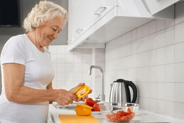 Donna anziana che fa insalata in cucina