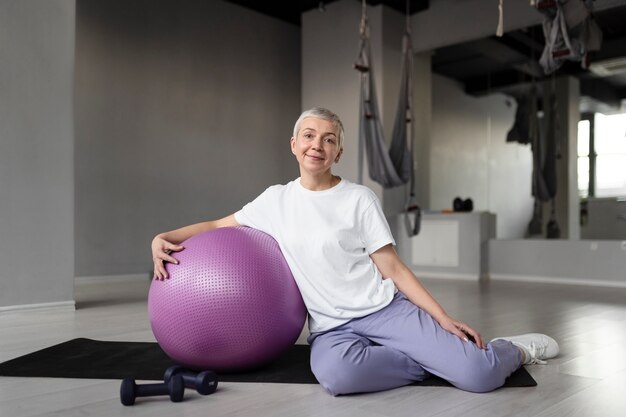 Donna anziana che fa un allenamento con la palla da ginnastica in palestra