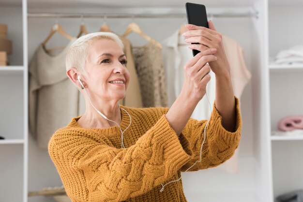 Donna anziana che prende un selfie e che ascolta la musica sulle cuffie