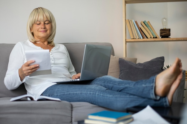 Donna anziana che segue una lezione online sul suo laptop a casa