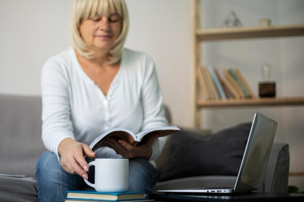 Donna anziana che segue una lezione online sul suo laptop a casa