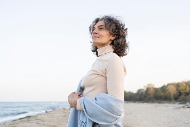 Donna anziana che si gode il tempo in spiaggia