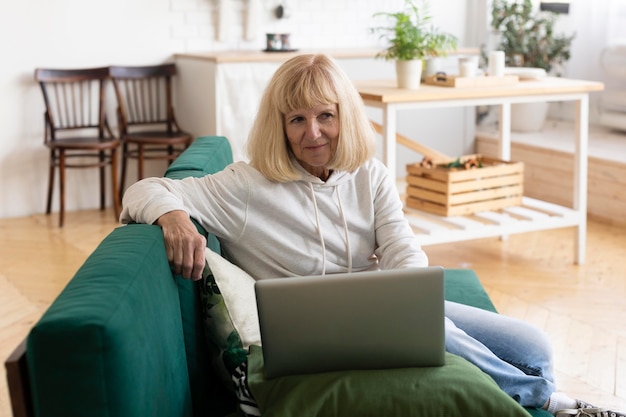 Donna anziana che utilizza computer portatile a casa