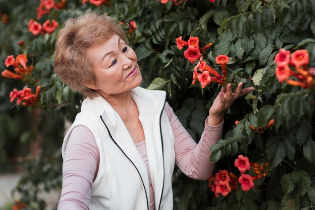 Donna anziana del colpo medio che posa con i fiori