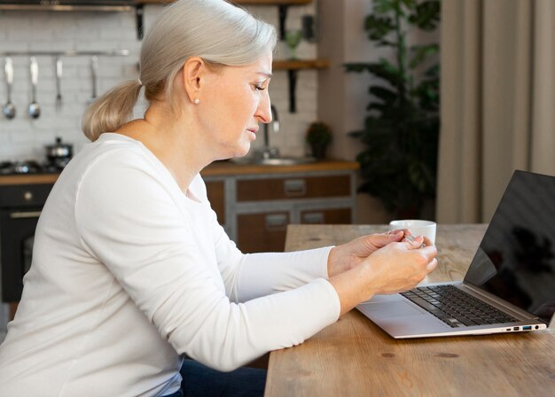 Donna anziana del colpo medio con il computer portatile