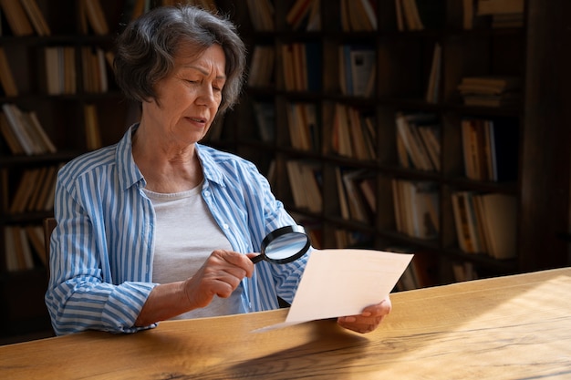 Donna anziana del colpo medio in biblioteca